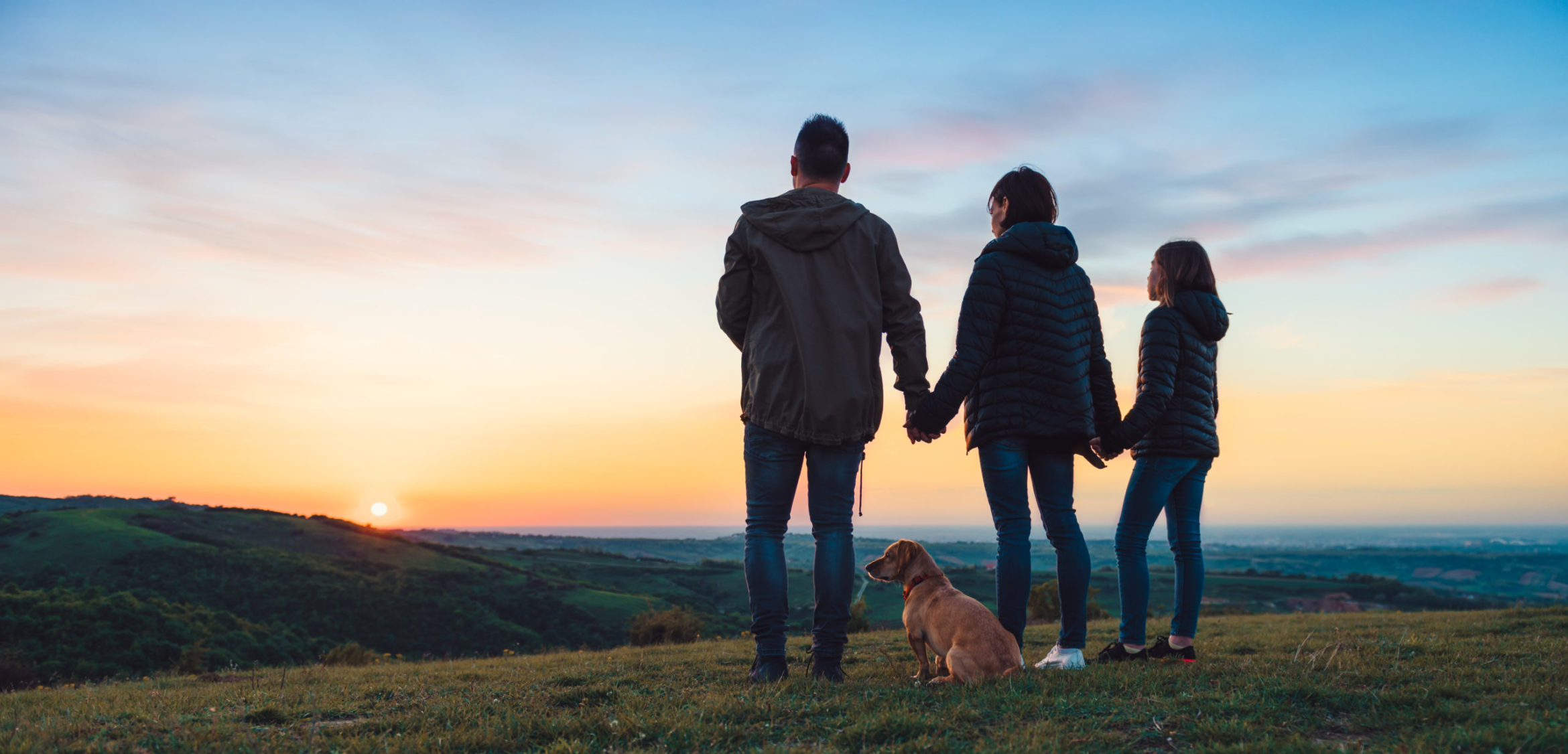 family-with-dog-embracing-while-standing-hill-scaled.jpg